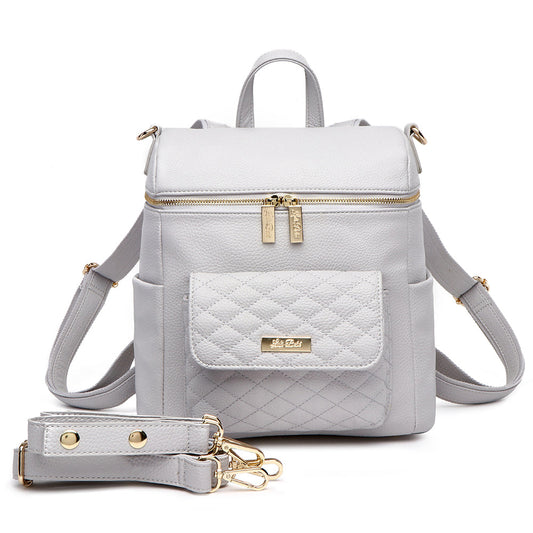 A stone grey Petit Monaco diaper bag made from vegan leather, featuring a compact design with multiple pockets and a quilted pattern. Includes a detachable strap and a signature logo zipper pull.
