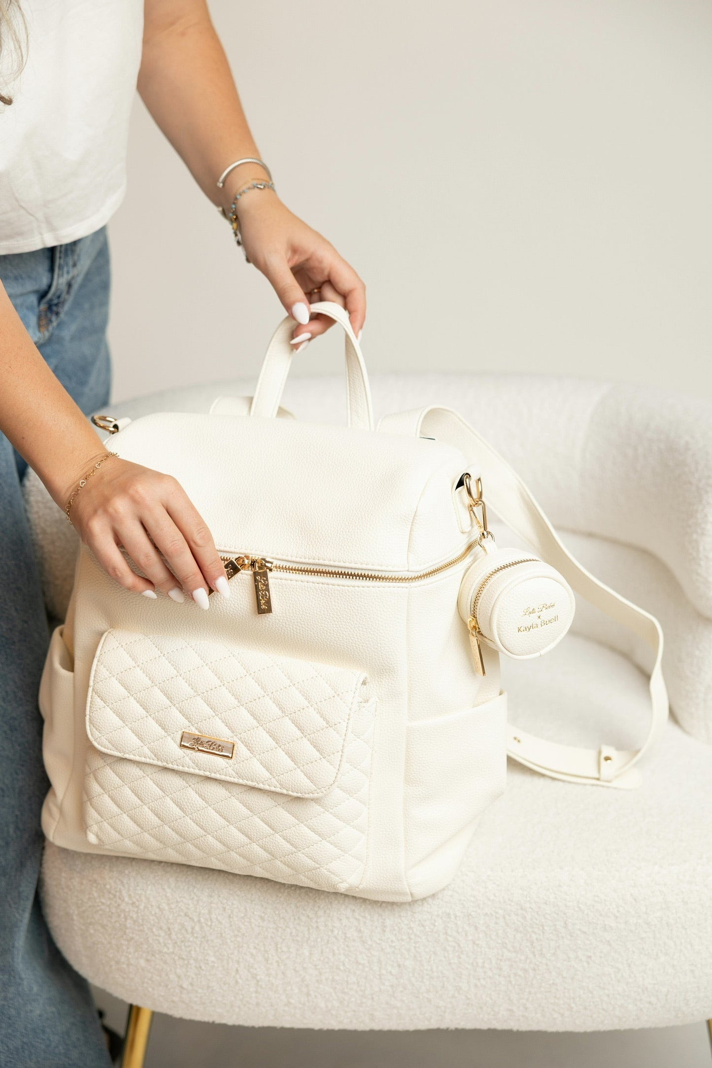 White quilted handbag held by a person on a light gray surface