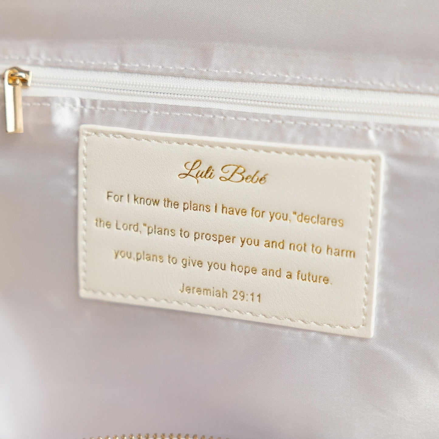 Lulu Belle pouch with a gold label featuring a biblical quote on a white background