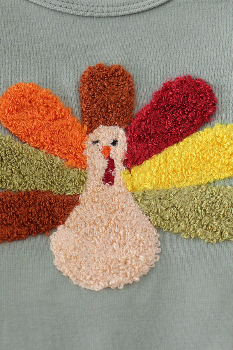 Colorful embroidered turkey design on a fabric background