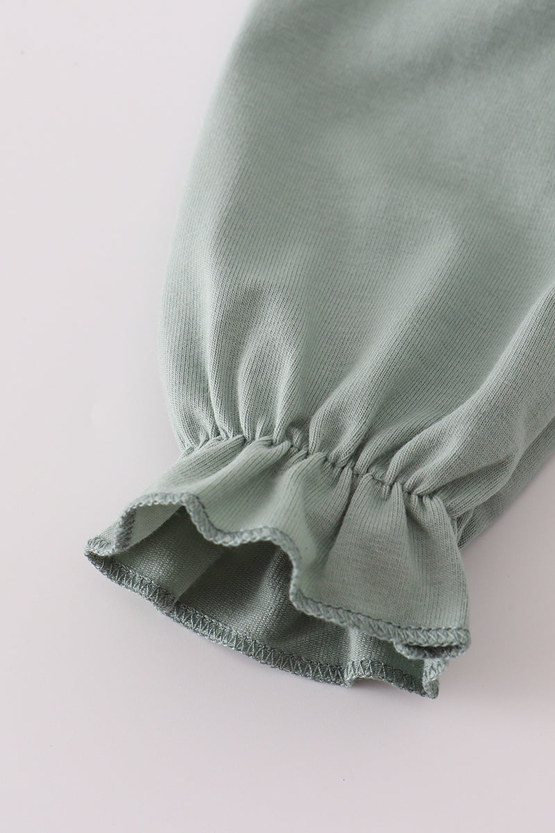 Green fabric with ruffled edge on a light gray background