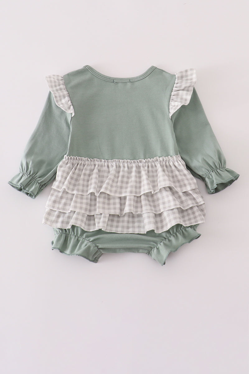 Green baby romper with ruffled layers on a light gray background