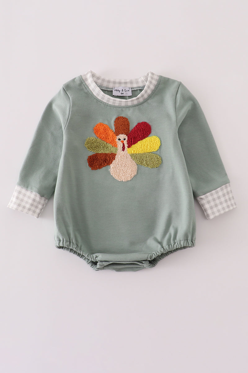 Green baby romper with embroidered turkey design on a light gray background