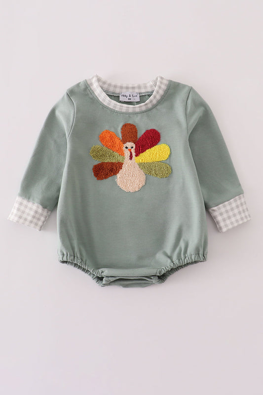 Green baby romper with embroidered turkey design on a light gray background