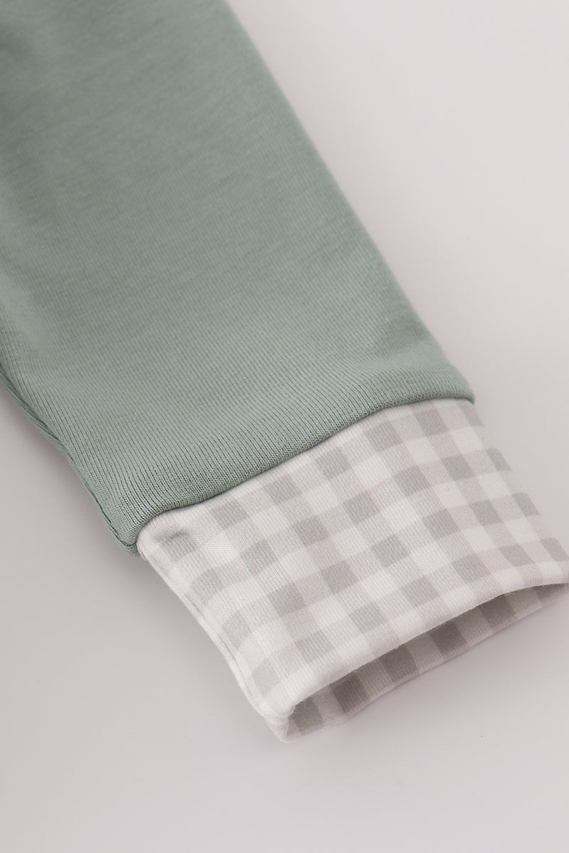 Close-up of a green fabric with a checkered pattern on a light gray background
