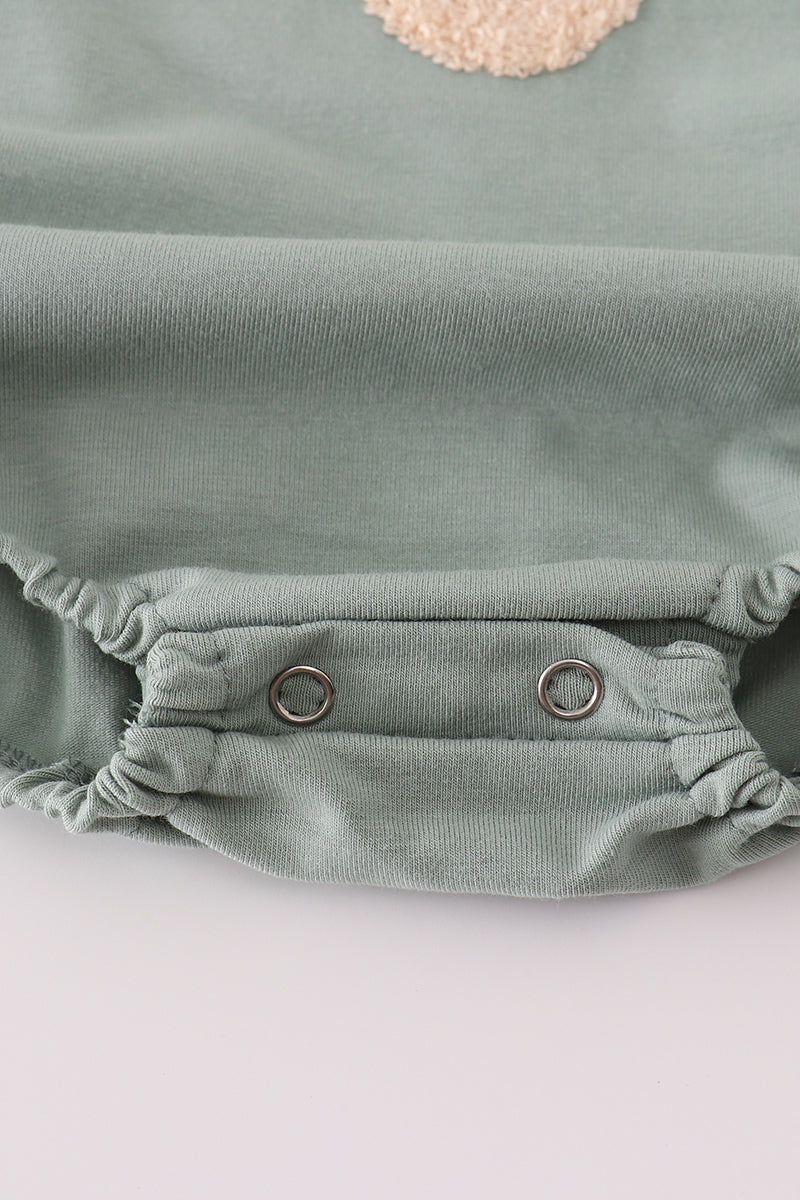 Green baby romper with buttons on a light gray background