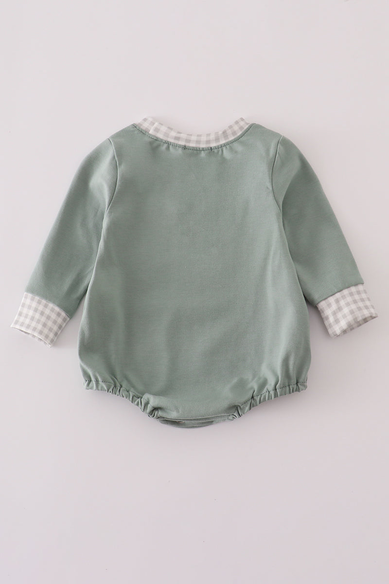 Green baby romper with checkered trim on a light gray background