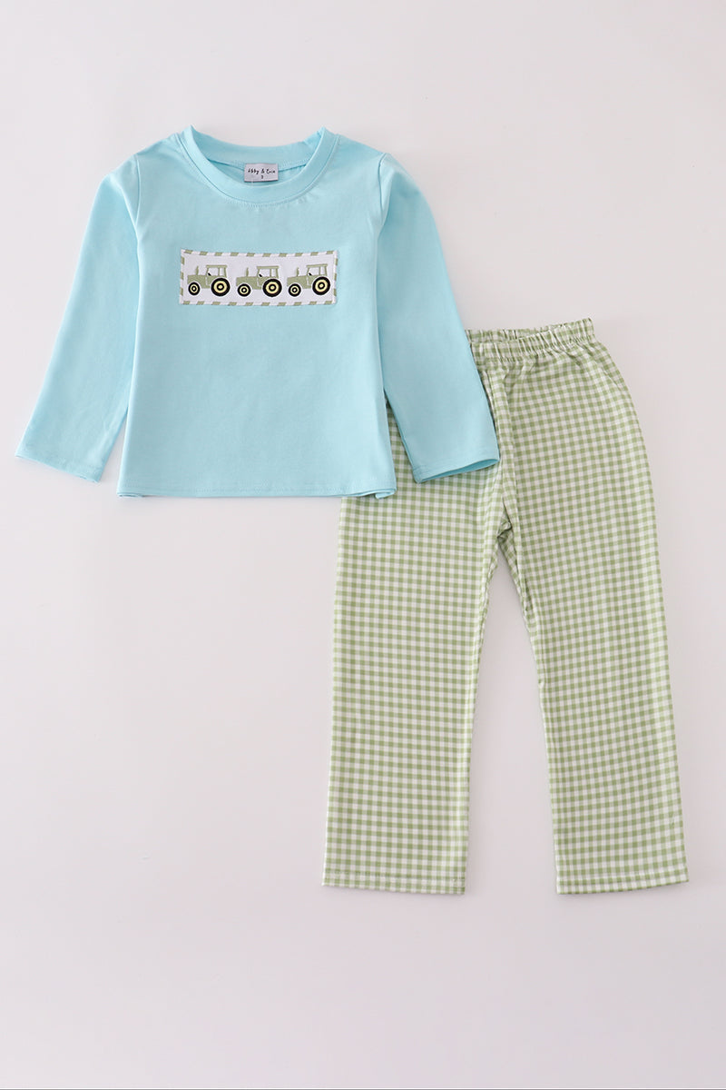 Children's outfit with light blue long-sleeve shirt and green checkered pants on a white background