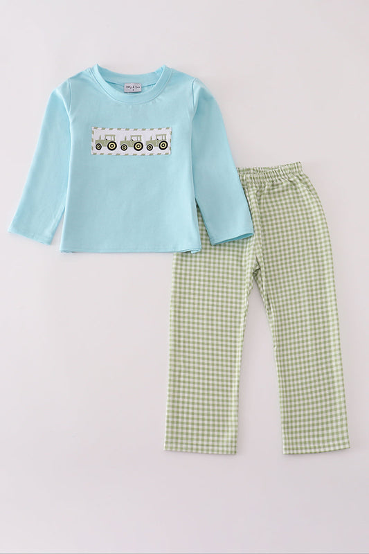 Children's outfit with light blue long-sleeve shirt and green checkered pants on a white background