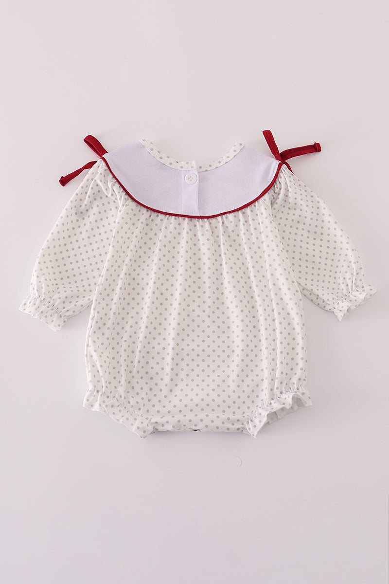White baby romper with red trim on a light gray background