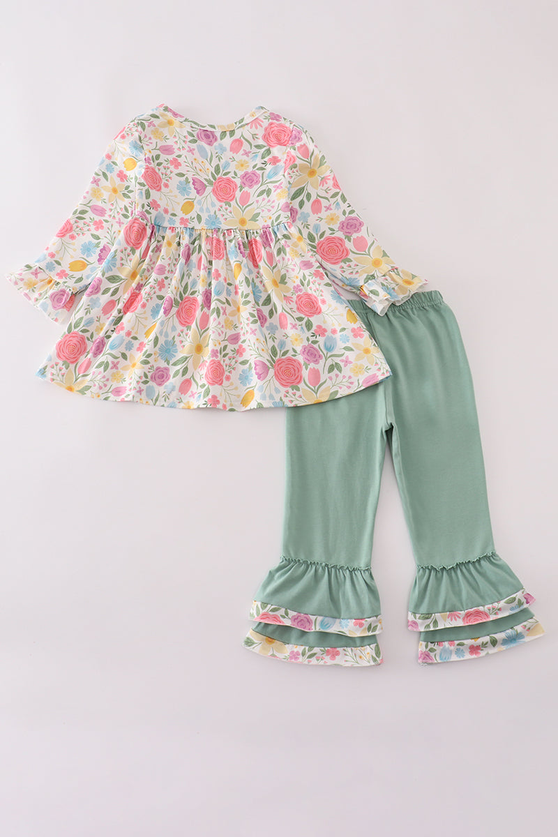 Children's floral top and green ruffled pants on a light gray background