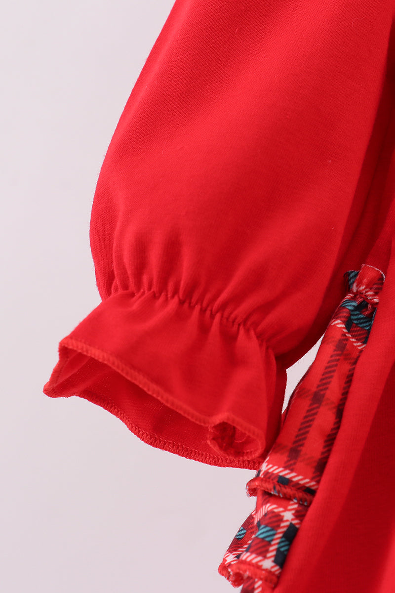 Close-up of a red garment with a patterned tie on a light gray background