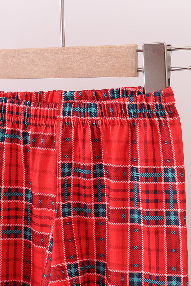 Red plaid fabric on a wooden hanger against a white tiled wall.