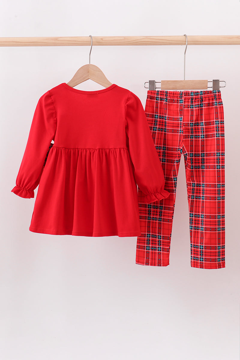 Red dress and plaid pants set on hangers against a white background