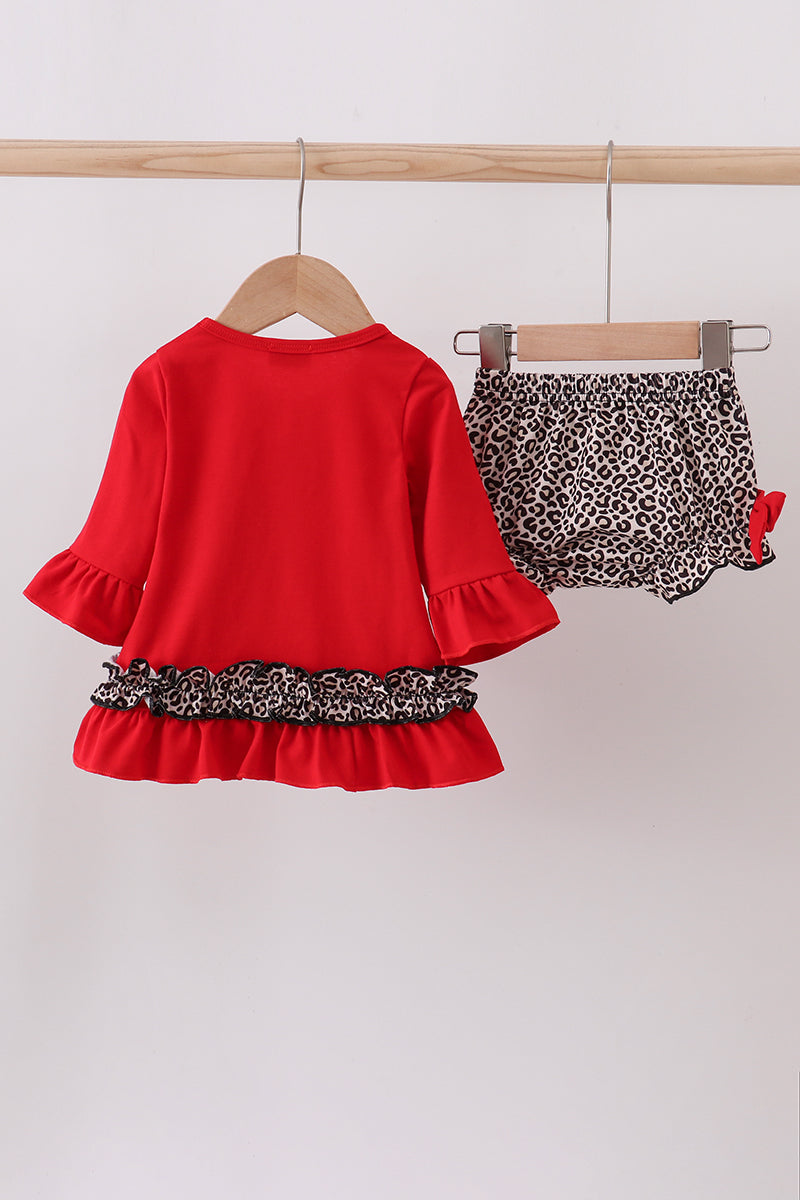 Red top with leopard print hem and matching shorts on hangers against a white background