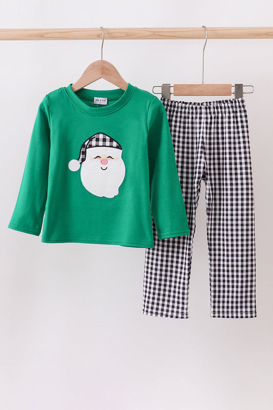 Children's green shirt with Santa Claus design and checkered pants on a hanger against a white background