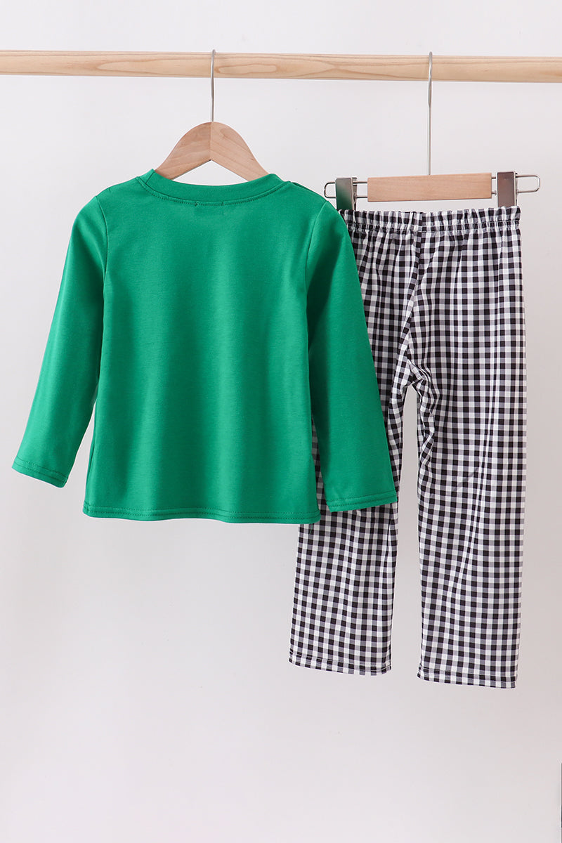 Green shirt and black and white checkered pants on hangers against a white background