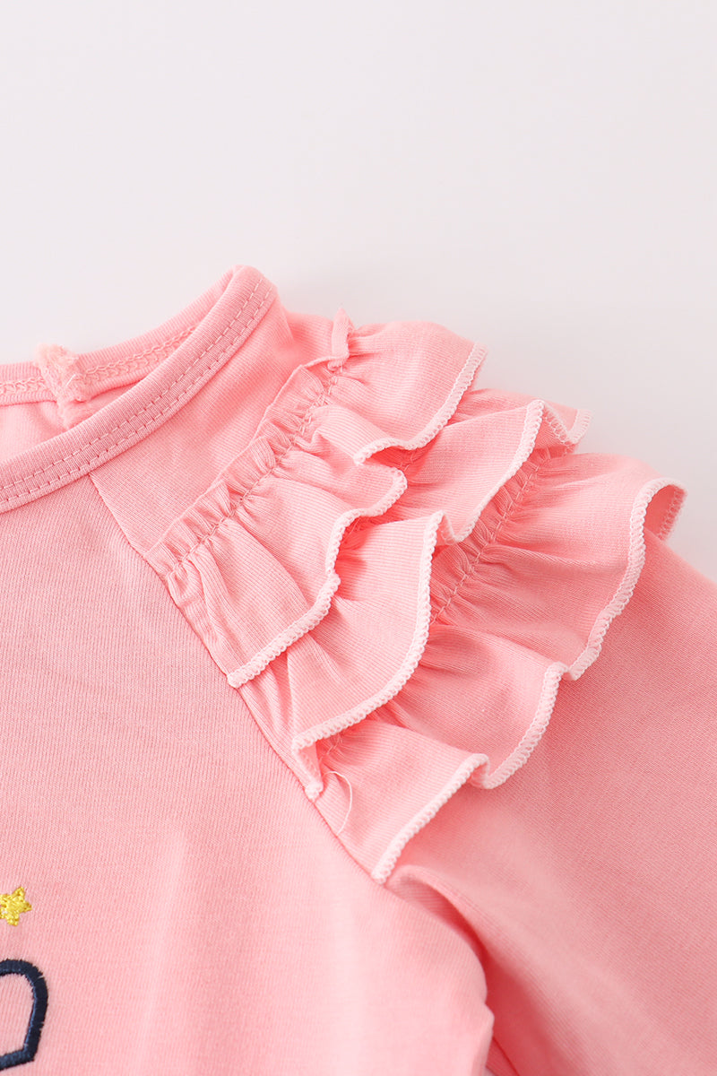 Close-up of a pink baby outfit with ruffled details on a light background