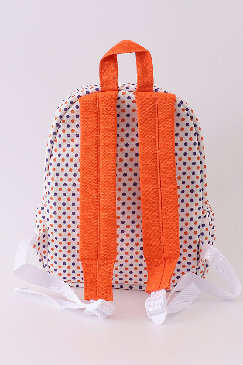 Backpack with orange straps and polka dot pattern on a plain background
