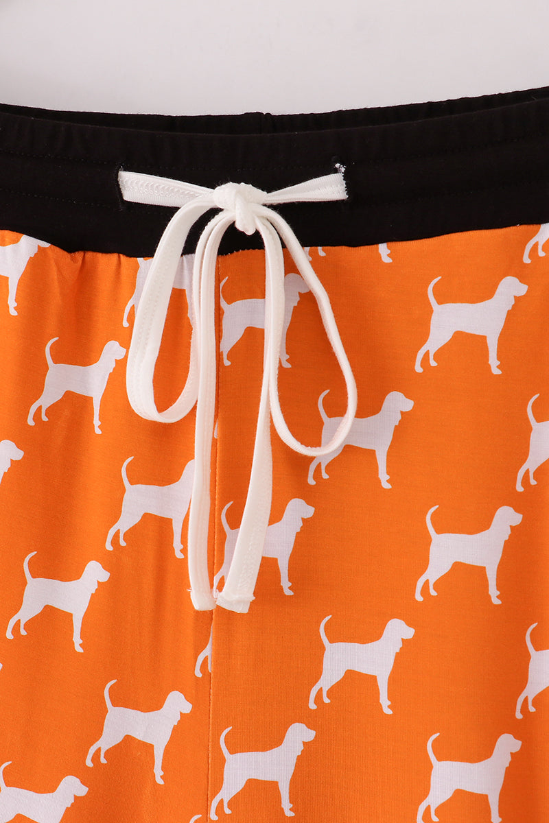 Orange shorts with white dog pattern and drawstring on a white background
