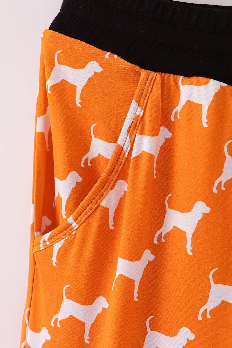 Orange shorts with white dog pattern on a plain background