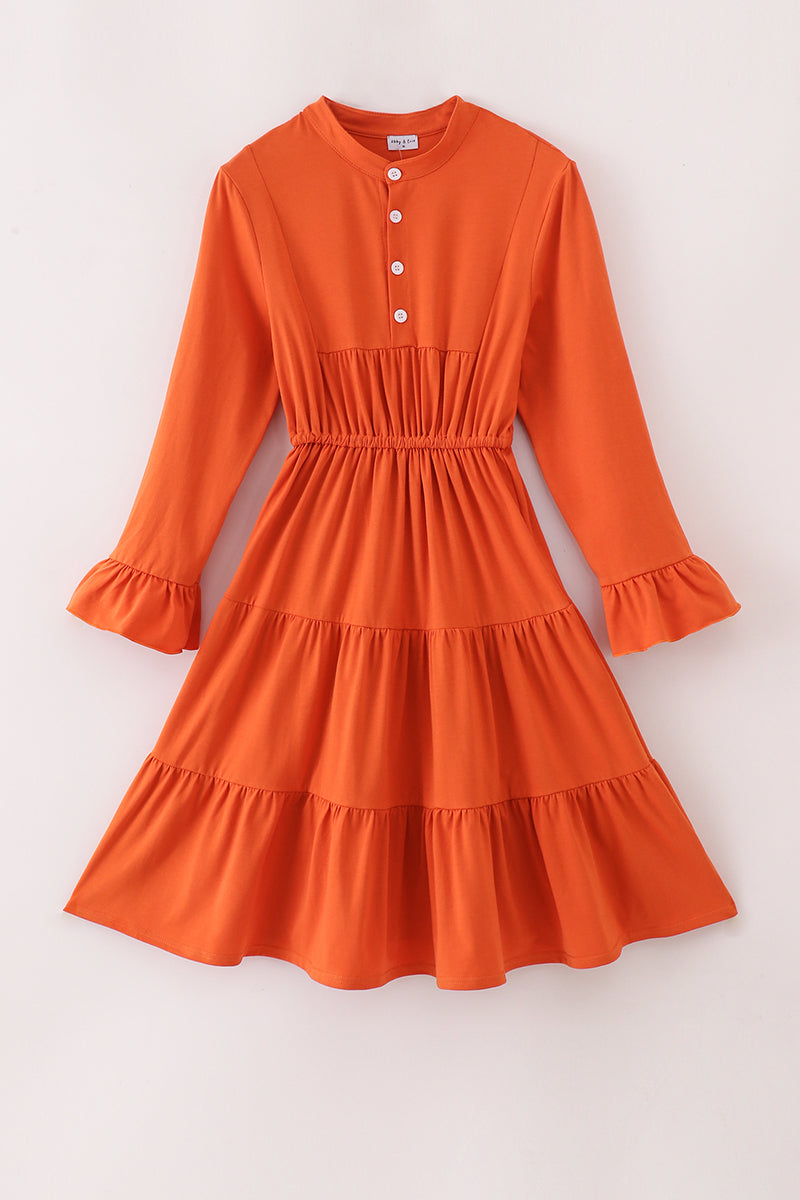 Orange dress with long sleeves and ruffled layers on a white background