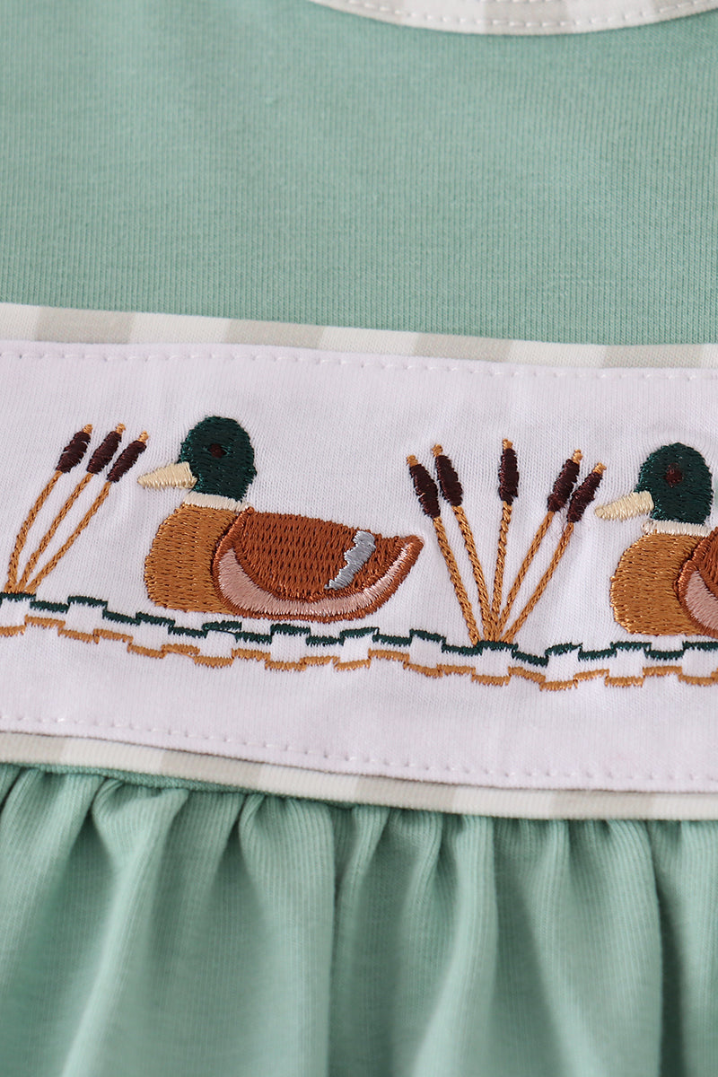 Green dress with embroidered ducks and reeds on a white background