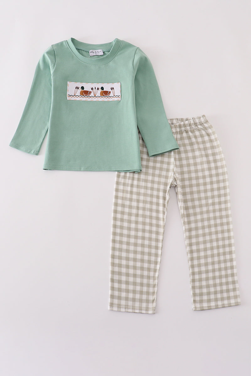 Children's green long-sleeve shirt with a graphic and checkered pants on a light gray background