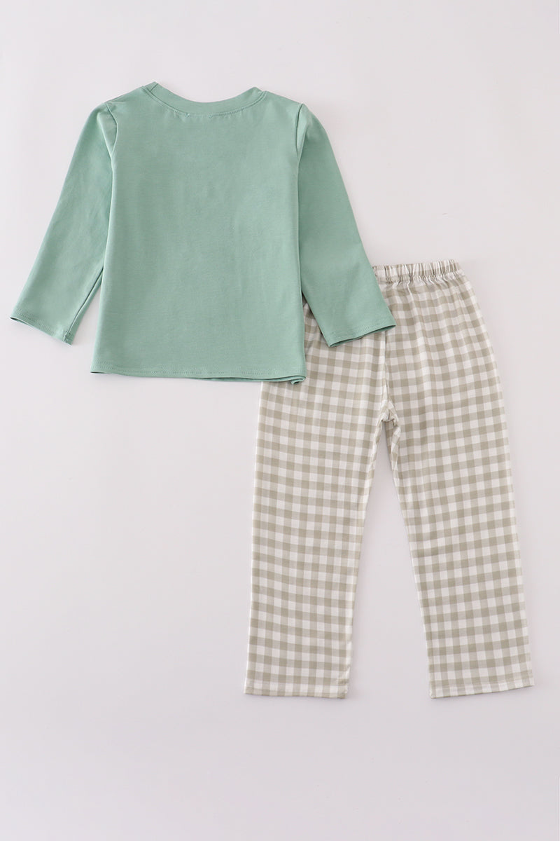 Green long-sleeve top and checkered pants on a light gray background