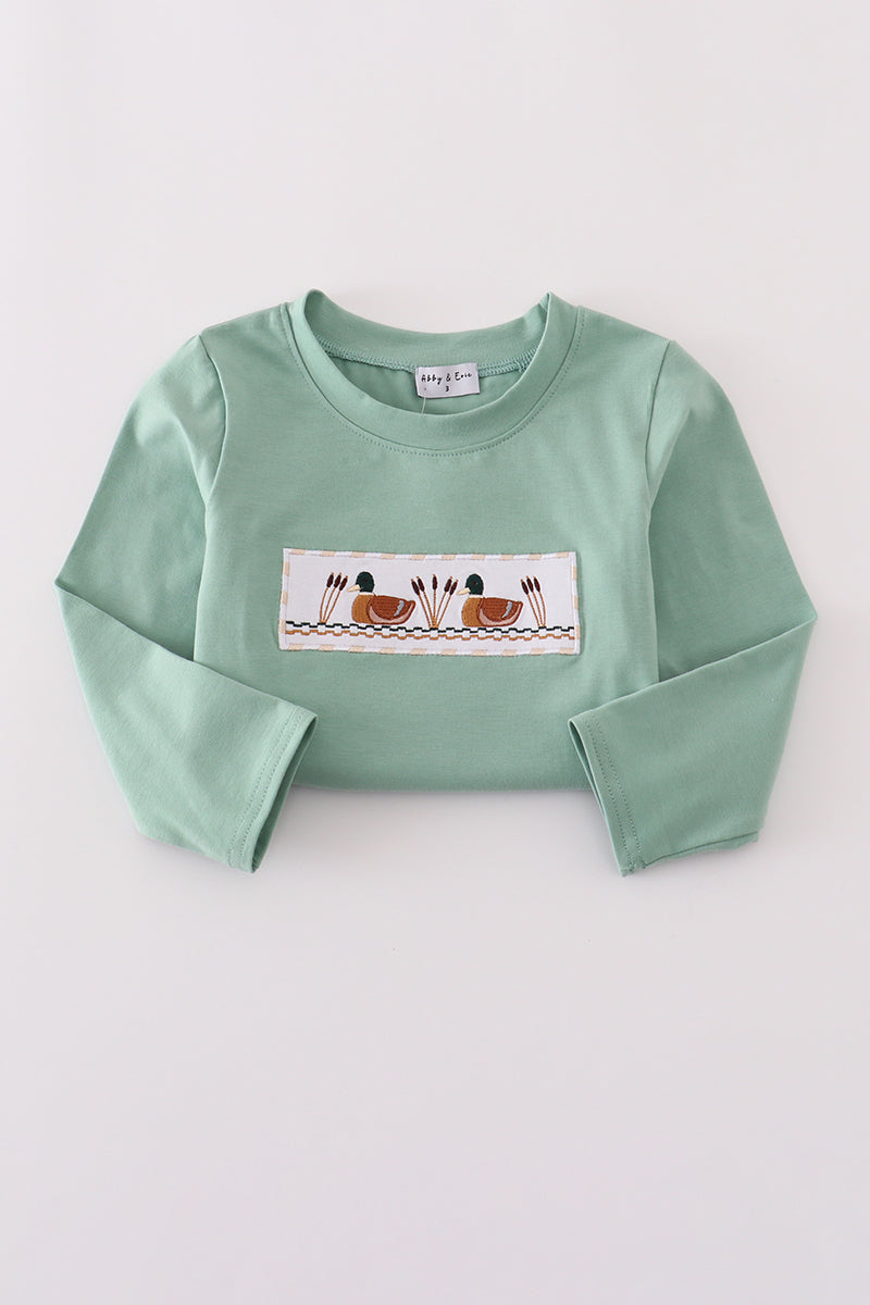 Green long-sleeve shirt with a graphic design on a light gray background