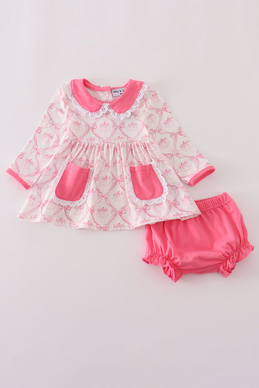 Baby girl's outfit with a pink and white dress and bloomers on a light gray background