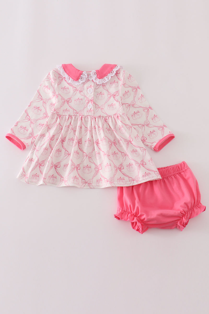 Baby dress and bloomers set with pink and white pattern on a light gray background