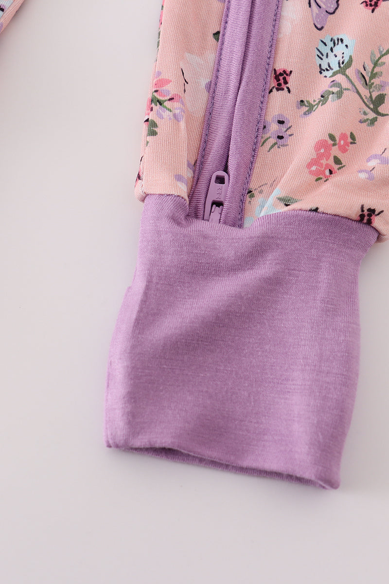 Close-up of a pink floral dress with a purple zipper on a light gray background