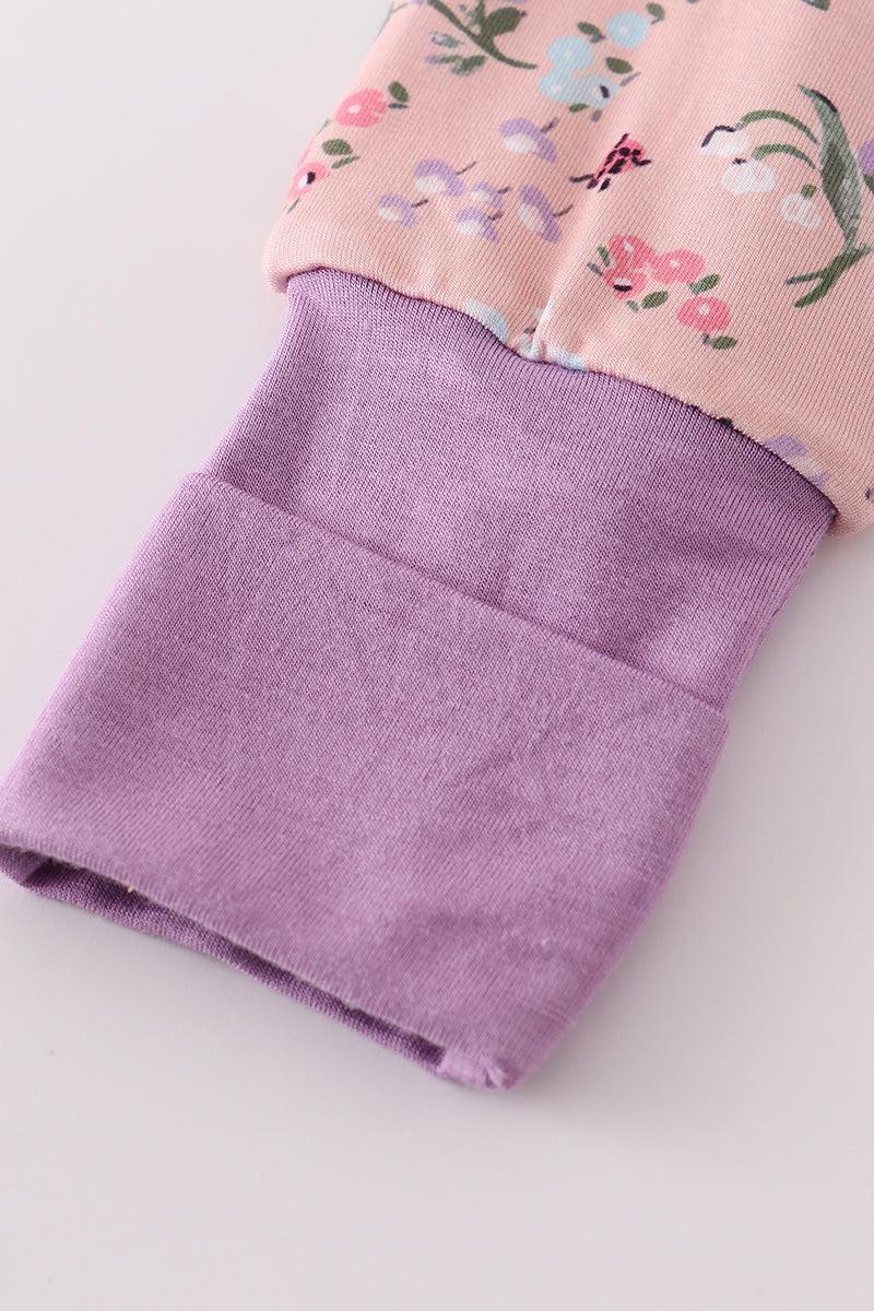 Close-up of a pink floral top and purple pants on a light background