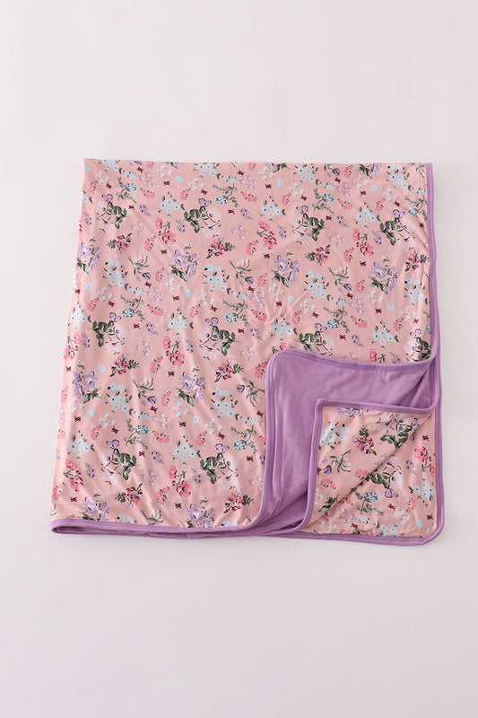 Floral-patterned blanket with a purple border on a light pink background