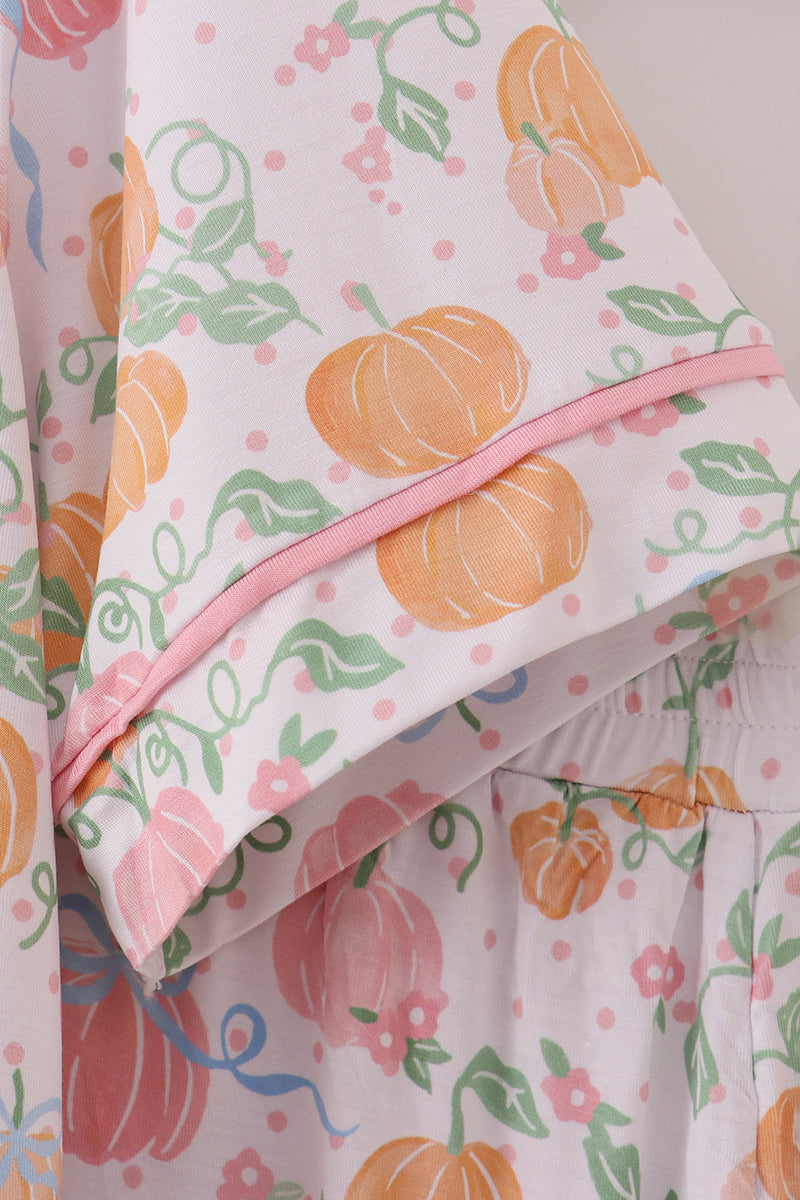 Floral and pumpkin patterned fabric with a pink zipper on a light background