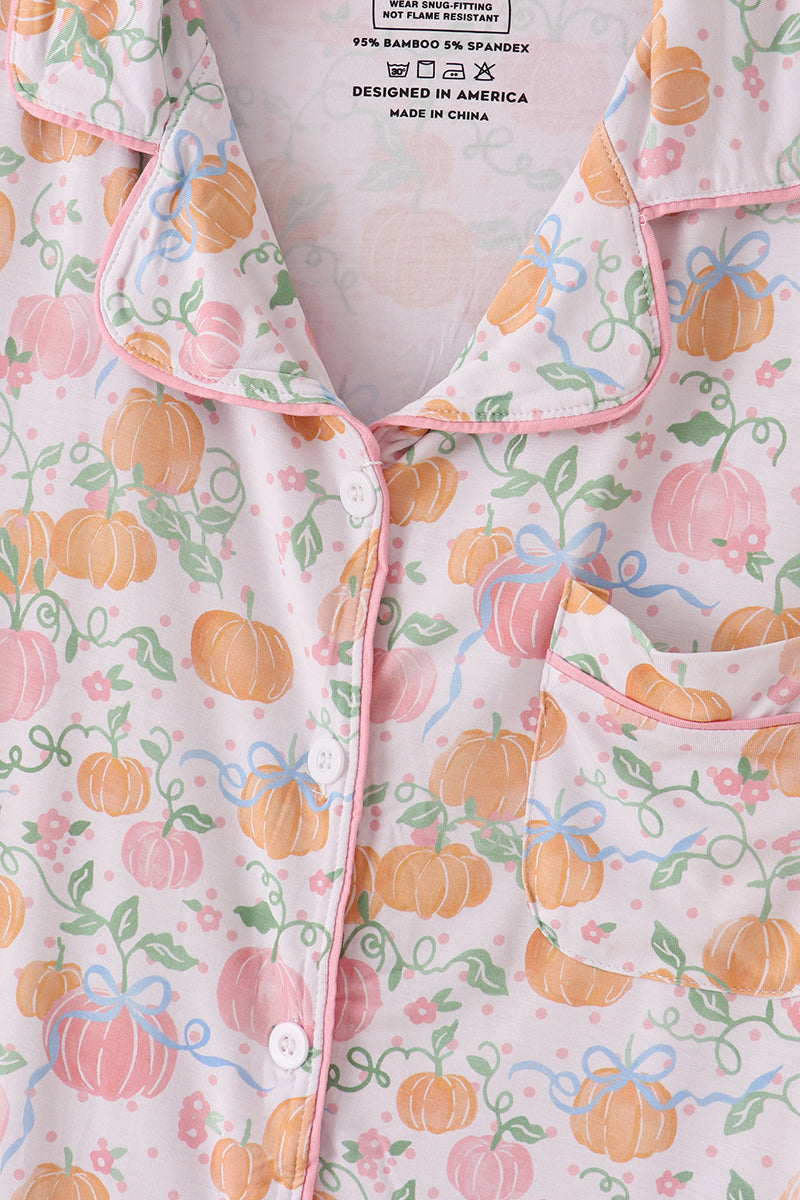 Floral patterned garment with pumpkins and pink trim on a white background