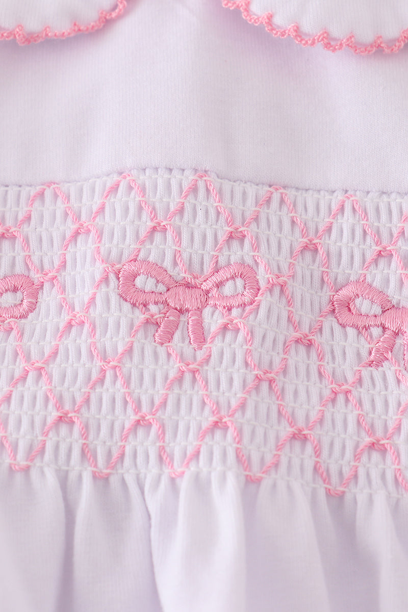 Close-up of a white garment with pink embroidery featuring butterfly designs.