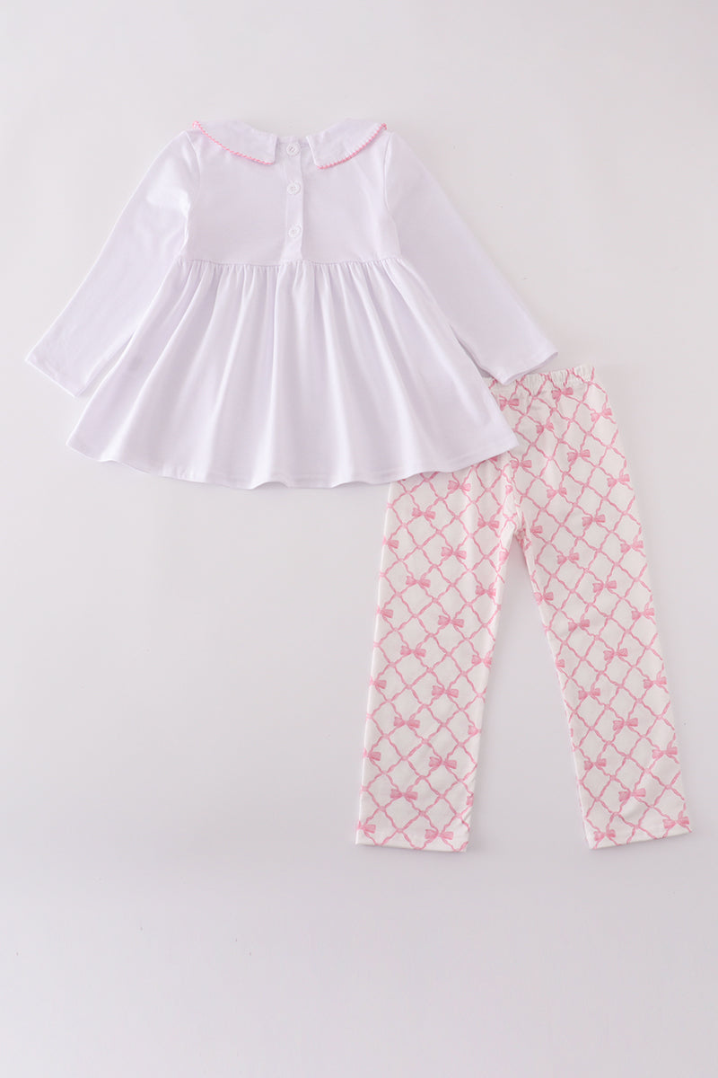 White top and pink patterned pants on a light gray background