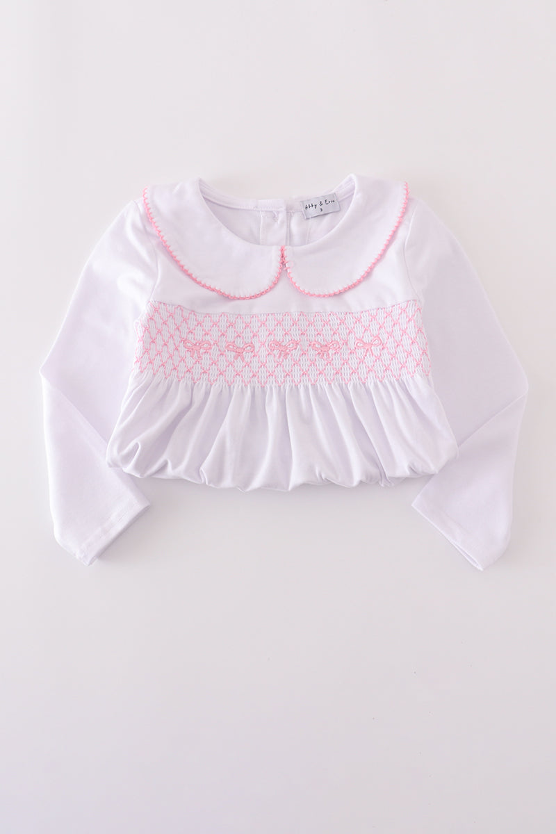 White blouse with pink smocked collar on a light gray background
