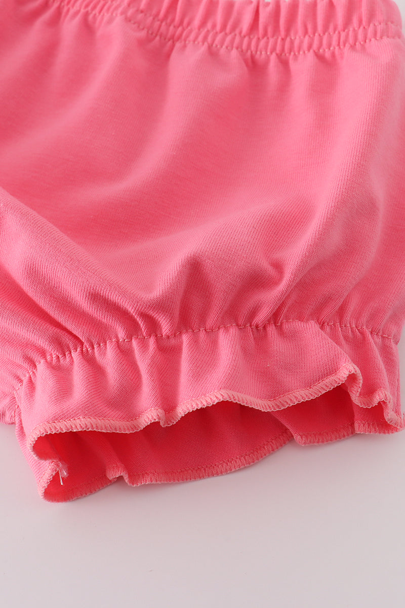 Close-up of pink shorts with ruffled hem on a light gray background