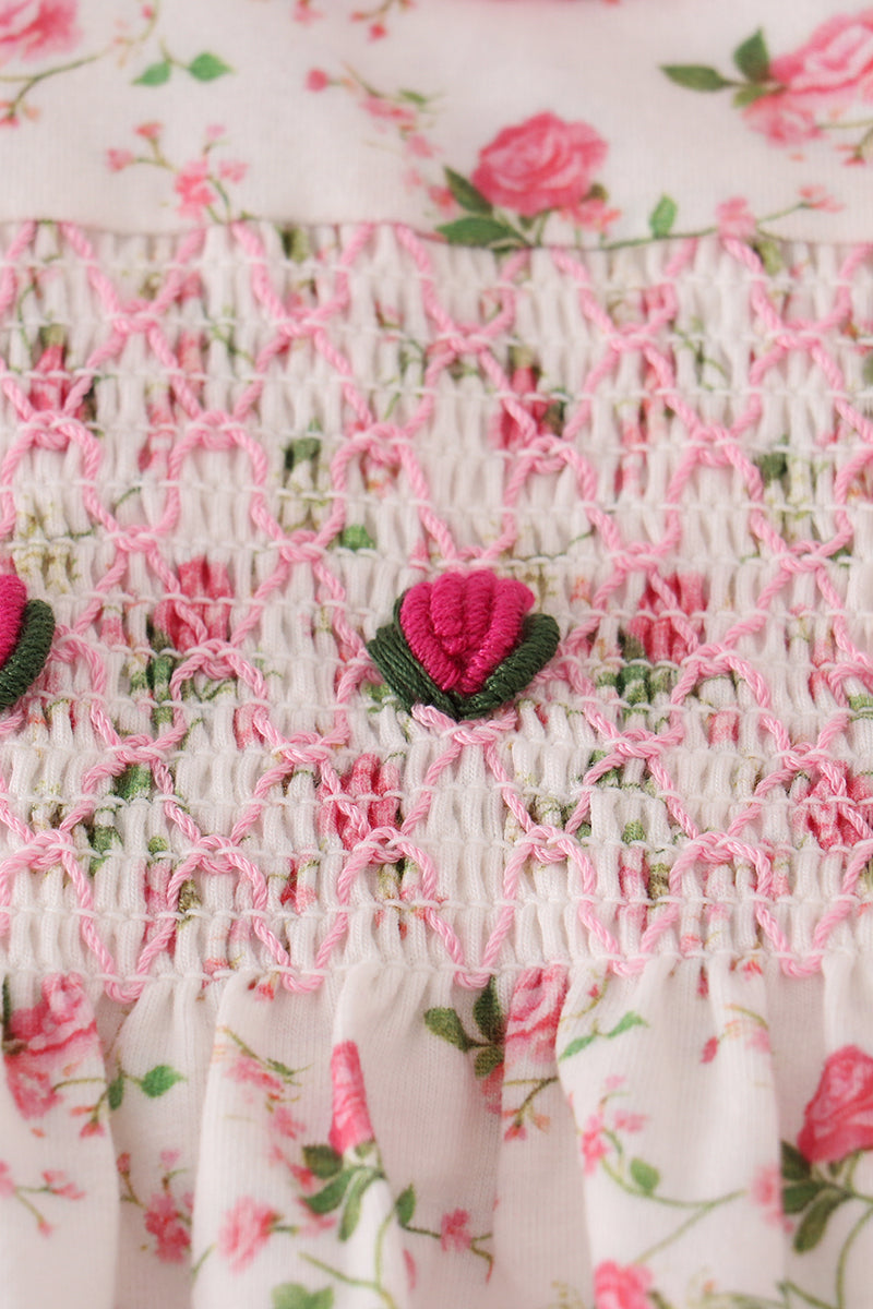 Close-up of a floral dress with pink roses and green leaves.