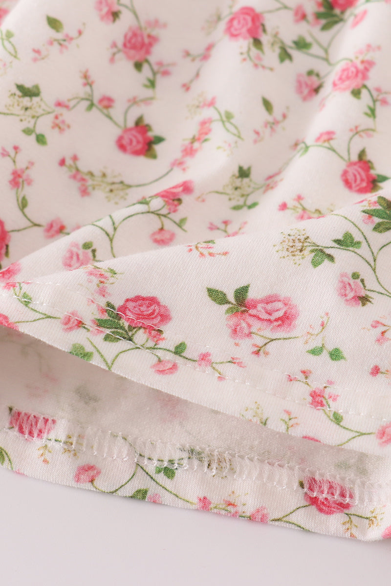 Floral fabric with pink roses and green leaves on a white background