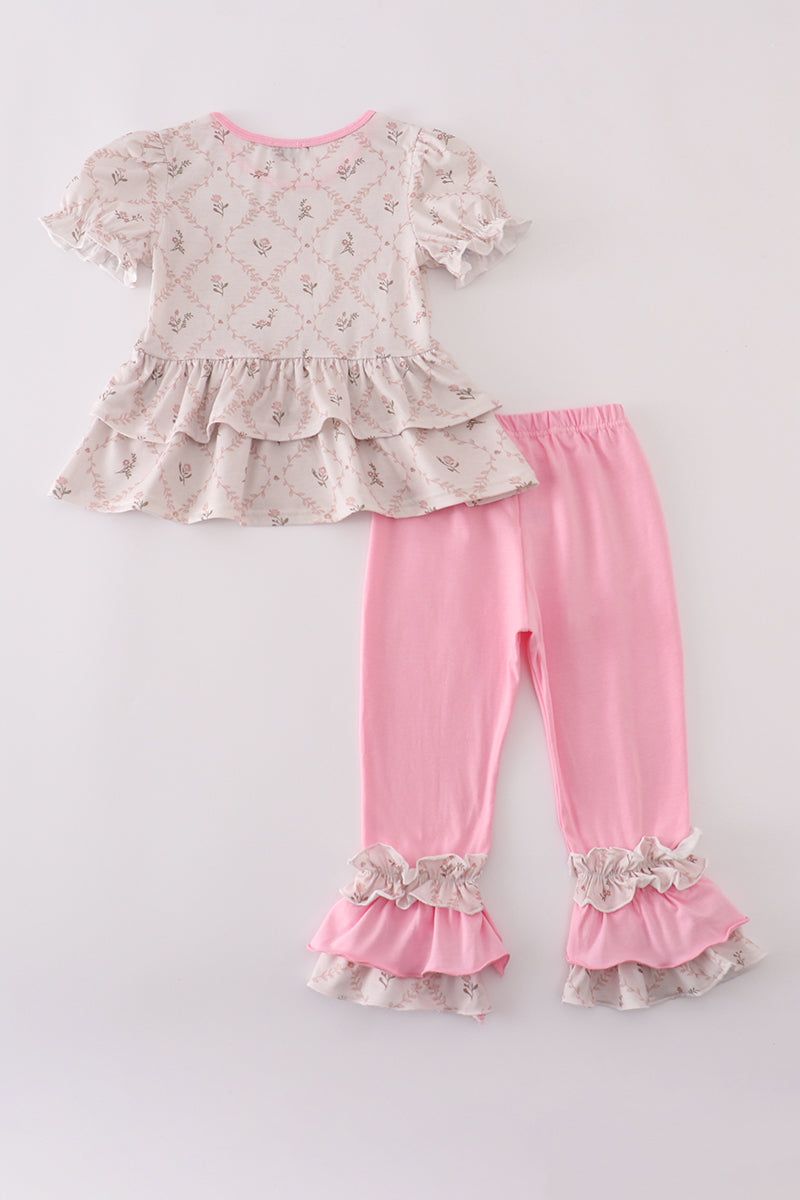 Children's outfit with floral top and pink pants on a light gray background