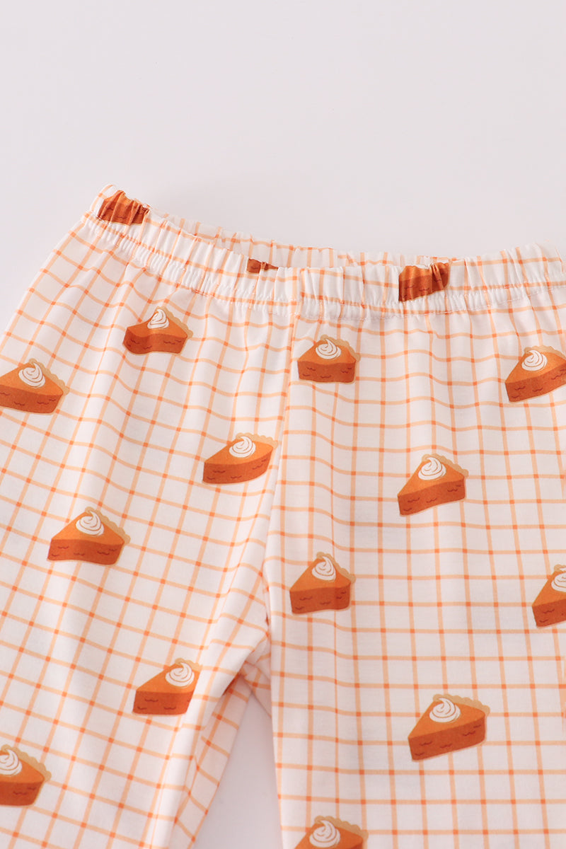 Plaid pajama pants with cake slice pattern on a light background
