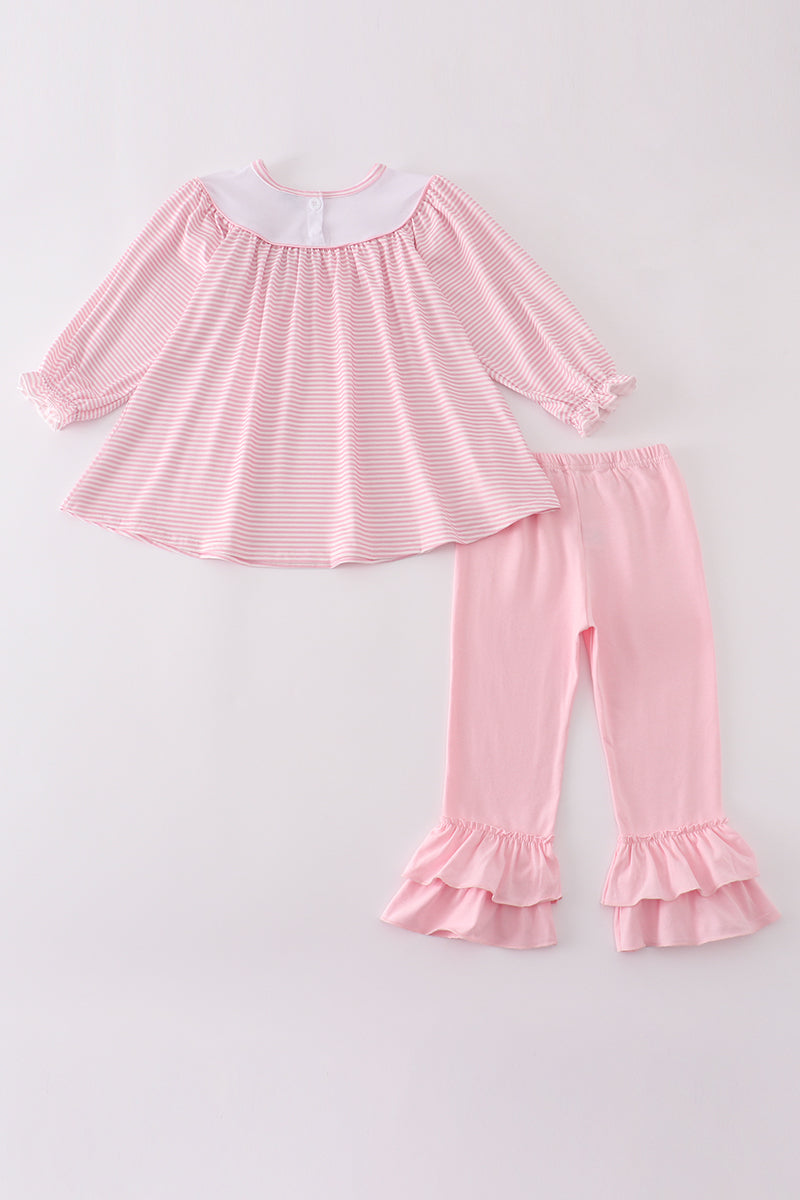 Pink pajama set with ruffled details on a light gray background
