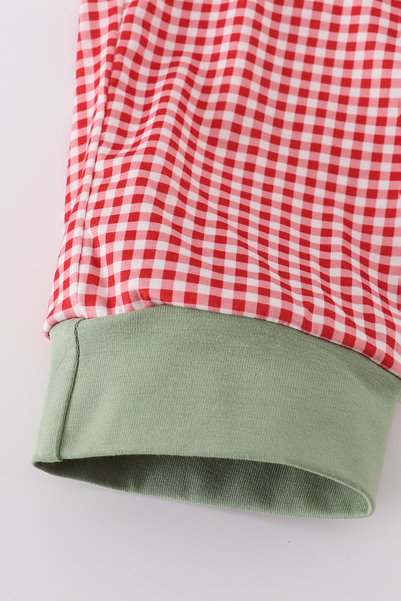 Red and white checkered fabric with green hem on a light gray background