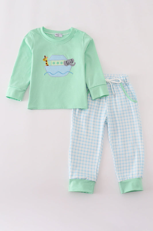Children's pajama set with green top and checkered pants on a light gray background