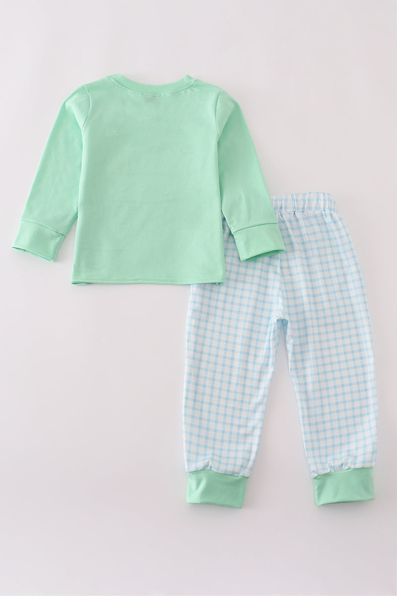 Children's pajama set with green top and checkered pants on a light gray background