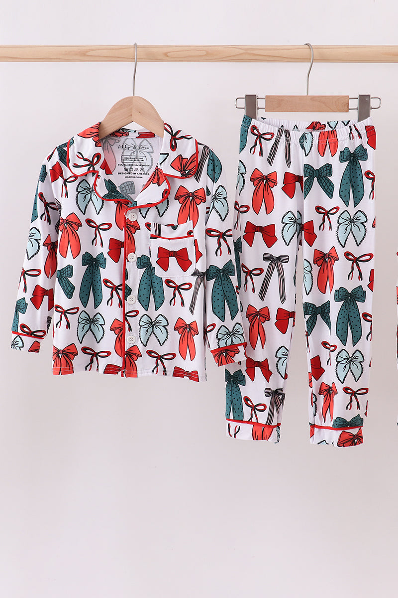 Pyjama set with bow pattern on hangers against a white background